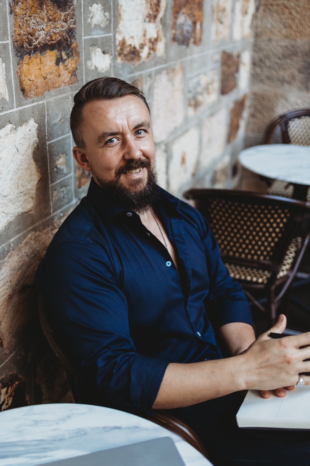 Anthony Clark, smiling, seated at a cafe table